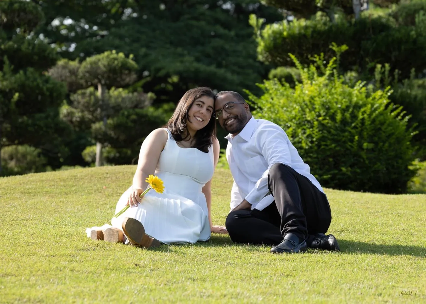 Ana y William sentados en la grama de un jardín, sonriendo